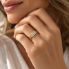 Bague Harmonie en or jaune 18 carats, trois diamants ronds au centre et monture croisée diamantée, portée au doigt d'une femme